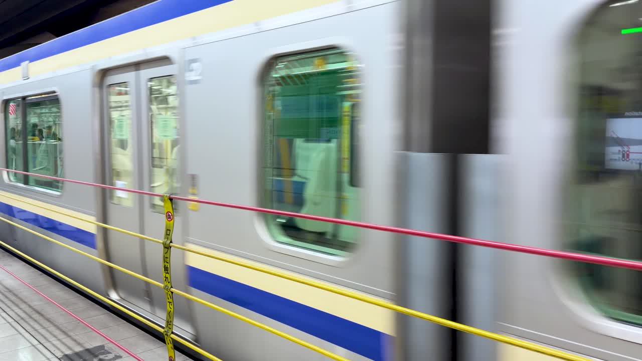 Un treno pendolare blu e argento entra in una moderna stazione sotterranea con sfocatura di movimento.