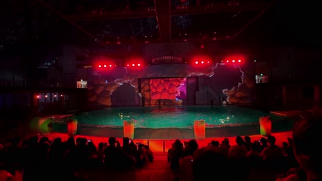aquarium show with bright red lighting and an indoor audience in tokyo under a dome at night