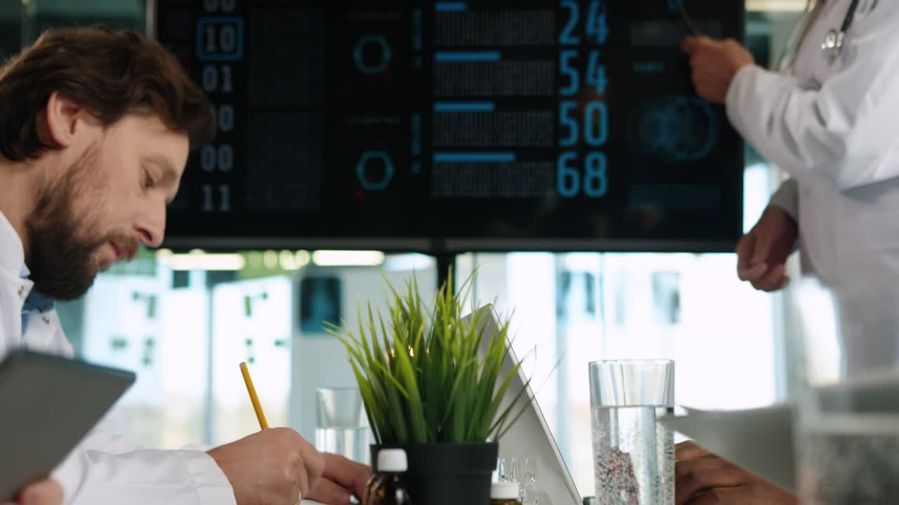 Close-up view of Multiethnic doctors team looking at digital screen presentation sitting at conference and discussing statistics of covid-19