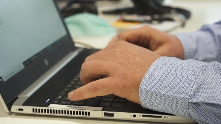 Face mask on desk next to male fingers typing on keyboard