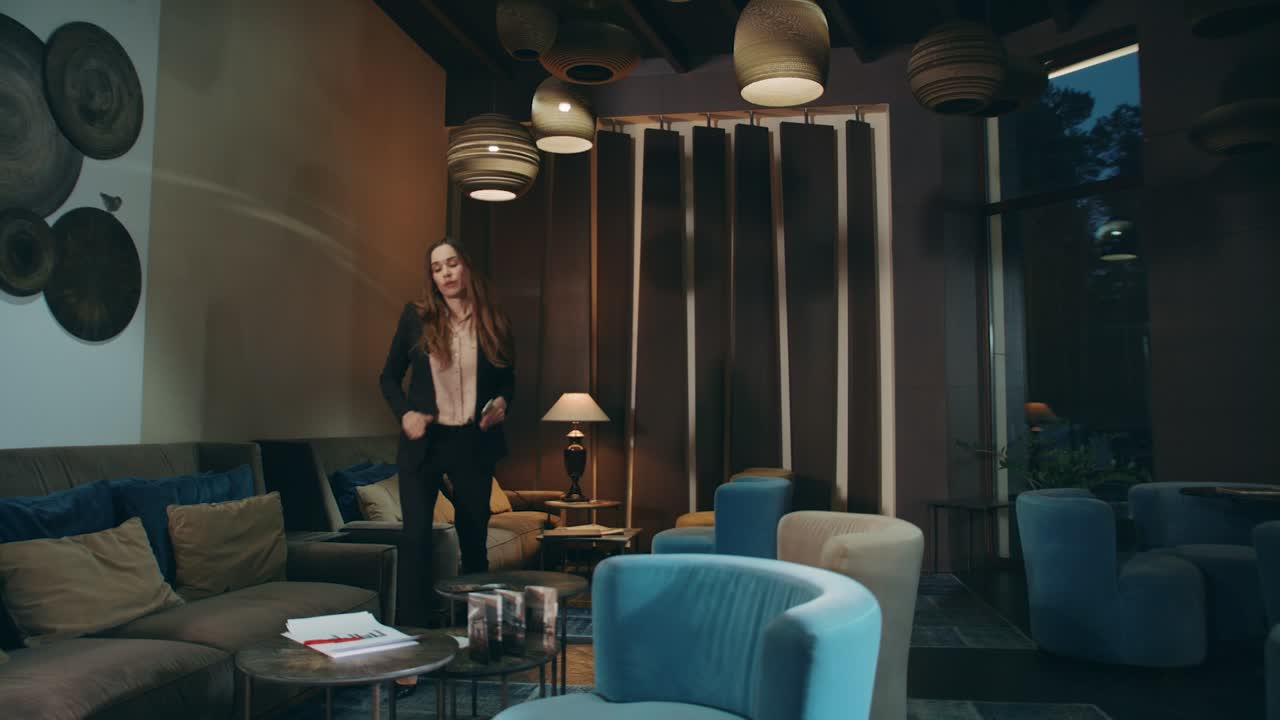 걱정 된 여자 는 호텔 로비 에서 기다리고 있다. 여자 는 라운지 에서 사업 문서 를 찾고 있다