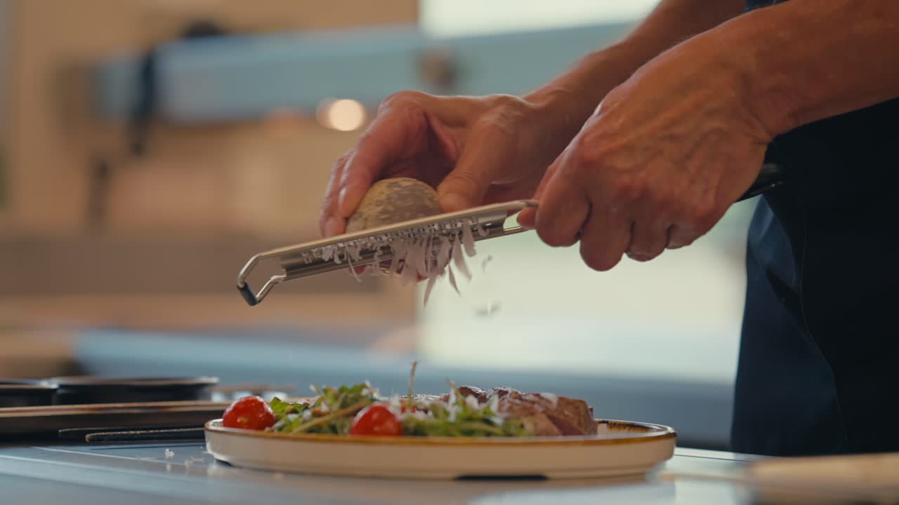Chef grate cheese on fresh salad and steak, close up