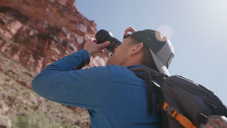 fotógrafo tomando una foto de paisaje de una montaña de roca roja en el desierto al aire libre en un día soleado brillante - cámara lenta