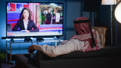 man watching news on cozy sofa