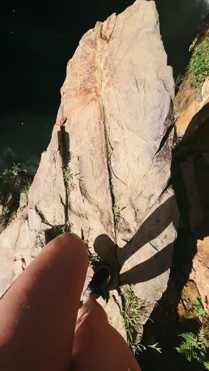 Person Standing on a Rocky Cliff Above a Waterfall