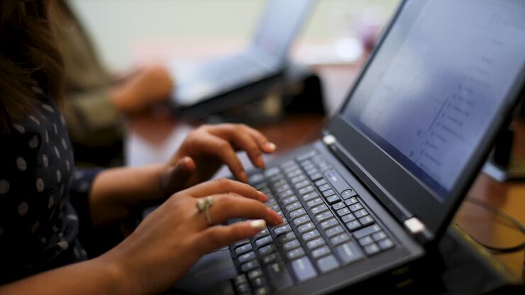 A woman's hand typing on a laptop keyboard from the side