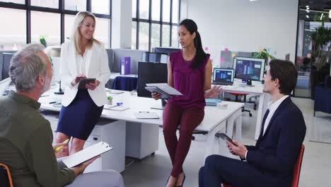 Diverse-business-colleagues-wearing-face-masks-having-casual-meeting-standing-in-office