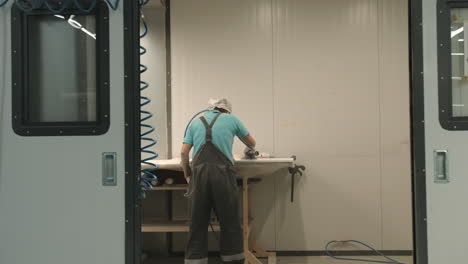 worker polishing or painting a surface in a manufacturing facility