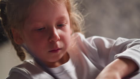 little artist with braids makes artwork with crayon at table