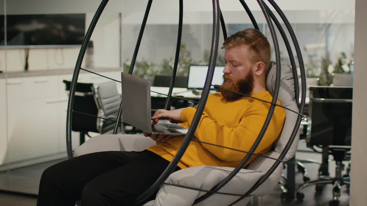 Man Working on Laptop in a Modern Office Swing Chair