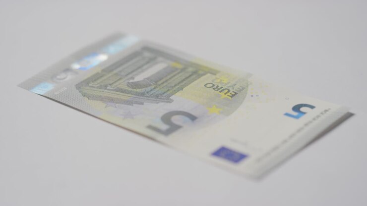 Gros plan en studio sur une main saisissant un billet de 5 euros