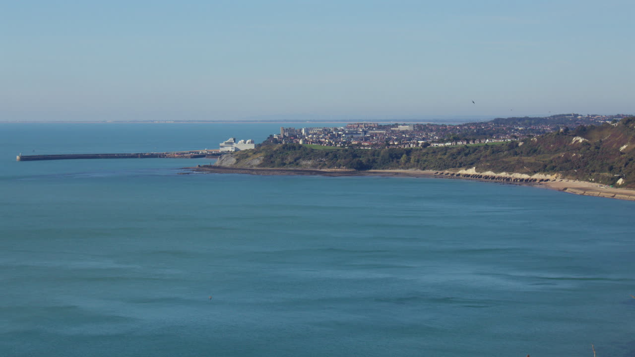 Vista panoramica di una città costiera, porto e spiaggia in una giornata di sole.