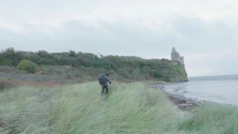 a videographer walking to his outdoors location at the beach