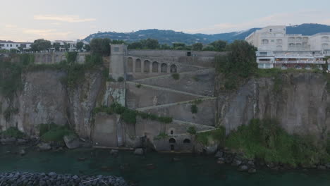 Aerial-footage-moving-towards-seaside-cliff-stairs-in-the-town-of-Sorrento,-Italy