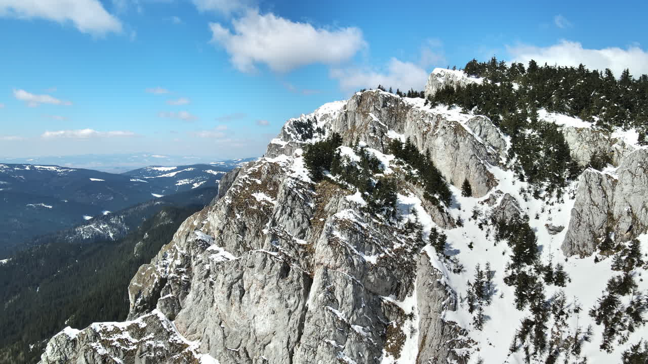 Vista aerea dei Carpazi in primavera, Romania, ripresa da un drone. Cime rocciose e valli parzialmente coperte da foreste innevate