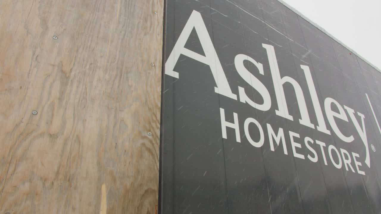 Sliding shot of Ashley Furniture HomeStore logo on side of delivery truck low angle, snow falling, bright sky