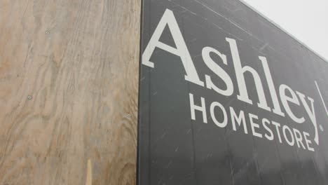 sliding shot of ashley furniture homestore logo on side of delivery truck low angle, snow falling, bright sky