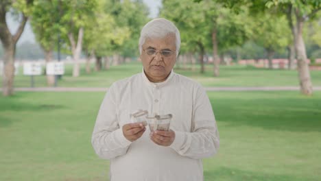 indian old man counting money in park