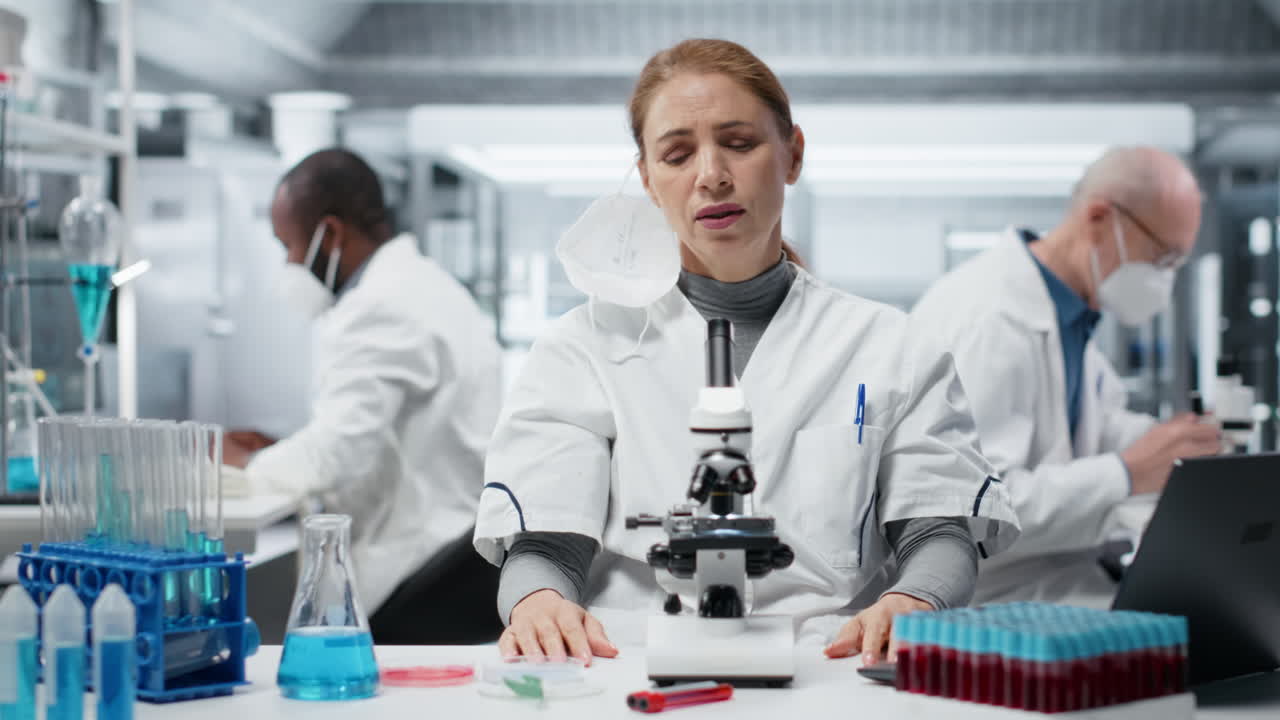 Biologo con mascherina chirurgica in un laboratorio medico usa un microscopio scientifico