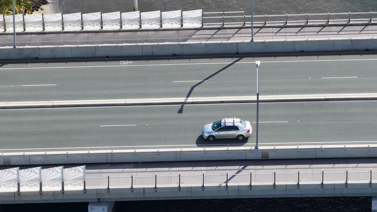 Aerial view of vehicles crossing a bridge on a sunny day in Gold Coast, Australia. Steady camera captures traffic flow