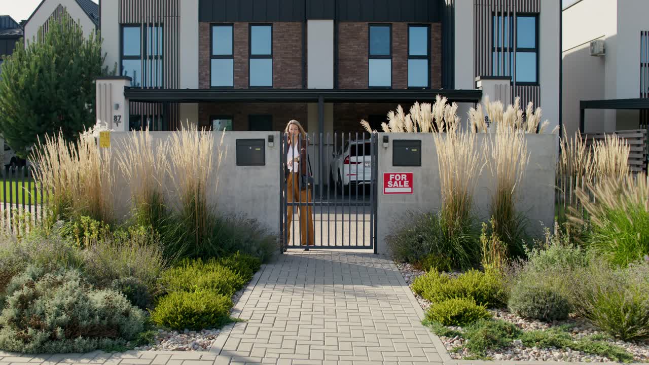 agente de bienes raíces hablando por teléfono frente a la casa en venta