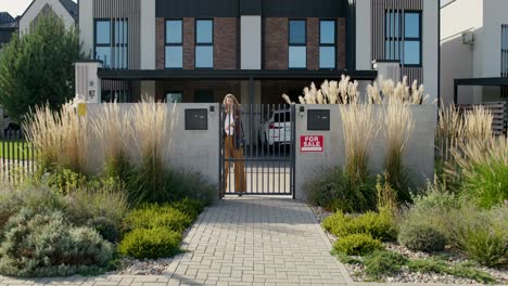 real estate agent talking on phone in front of house for sale