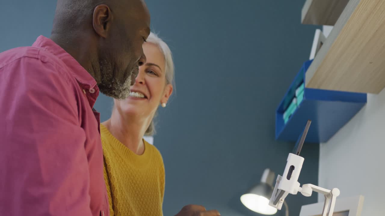 una feliz pareja diversa sentada a la mesa y hablando