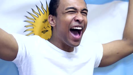 argentinian fan celebrating while holding the flag of argentina in slow motion