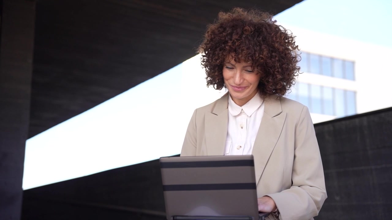 Una donna professionista lavora al suo laptop circondata da moderna architettura urbana.