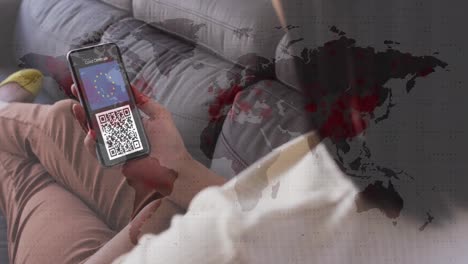 Woman-holding-a-smartphone-with-qr-code-on-screen-against-red-sports-spreading-over-world-map