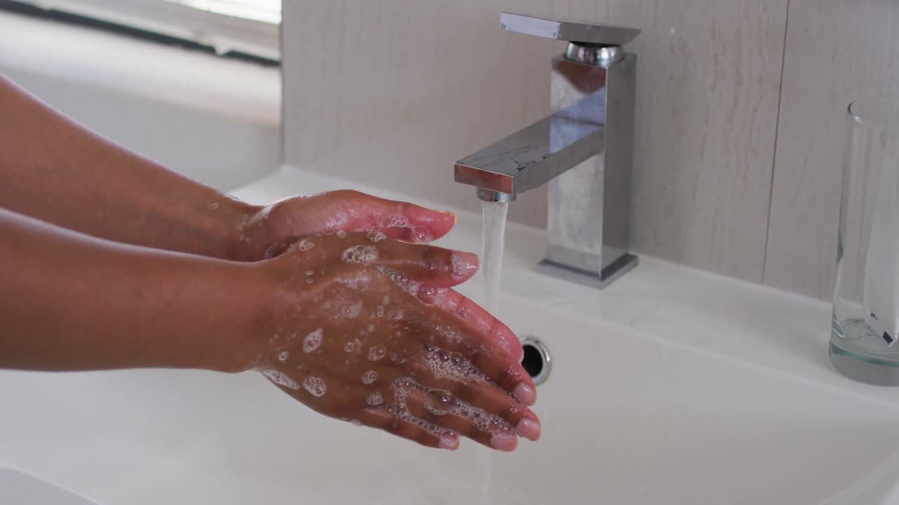 Close up of african american woman washing her hands in the bathroom sink at home