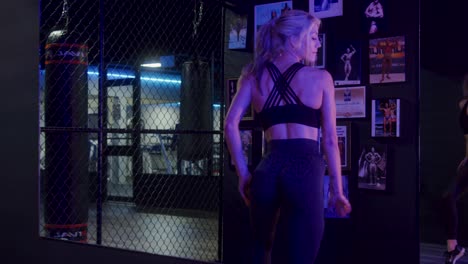 chica atlética posando frente a un espejo en un gimnasio preparándose para una competencia física