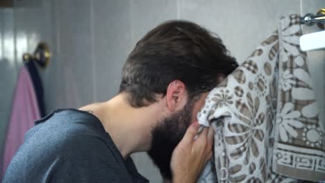 hombre secando la cara en el baño
