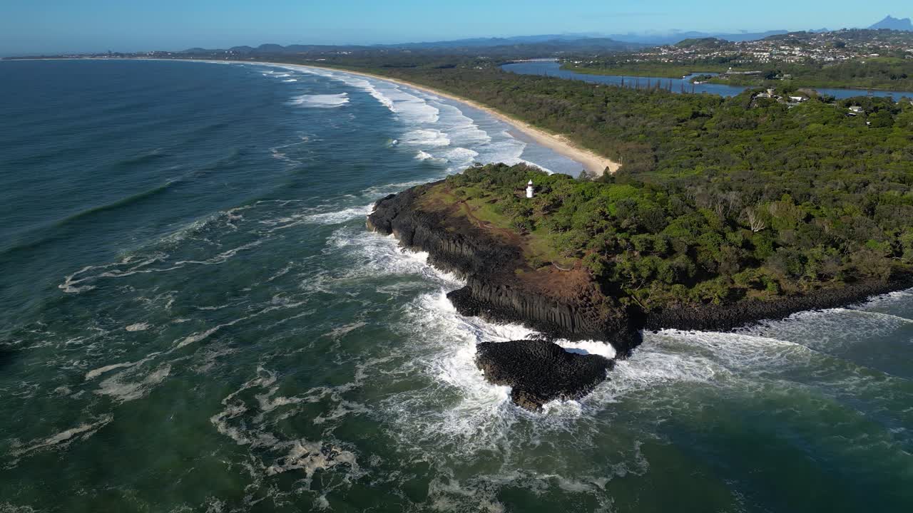 Right to left rotating aerial looking at Fingal Head Lighthouse from over the ocean on a sunny day, Northern New South Wales, Australia.