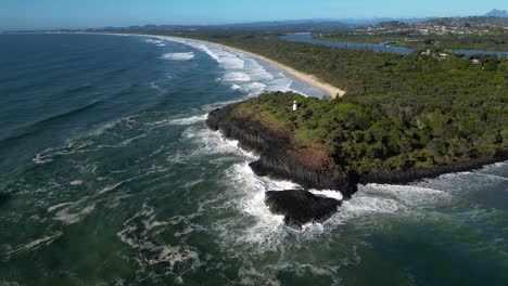 right to left rotating aerial looking at fingal head lighthouse from over the ocean on a sunny day, northern new south wales, australia.