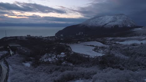 winter landscape view from mountain with snowy trees, city, and ocean