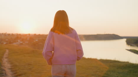 woman rests walking at sunset riverside relaxed slim lady spends tranquil evening on hilly bank of