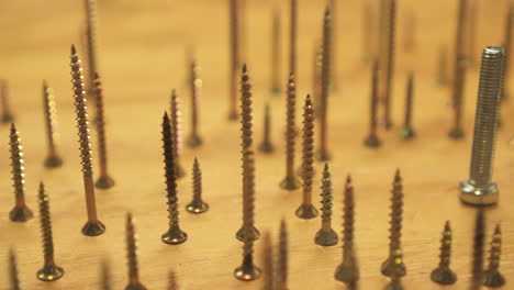 concept of odd one out, numerous bronze screws circle single large silver bolt