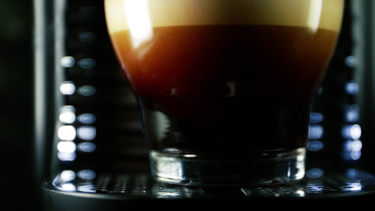 Various color froth Layers of expresso coffee being filled up on clear glass mug on cafe machine  - closeup macro shot