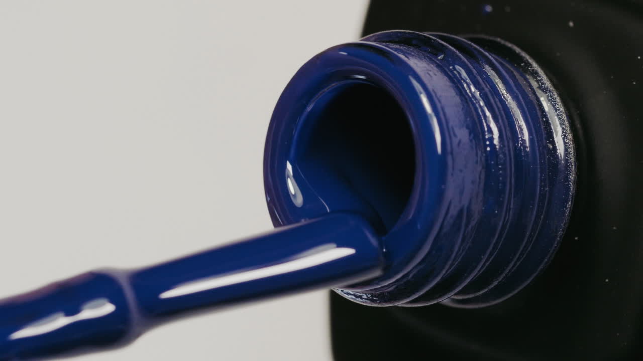 Close-up of dark blue nail polish being dispensed from bottle