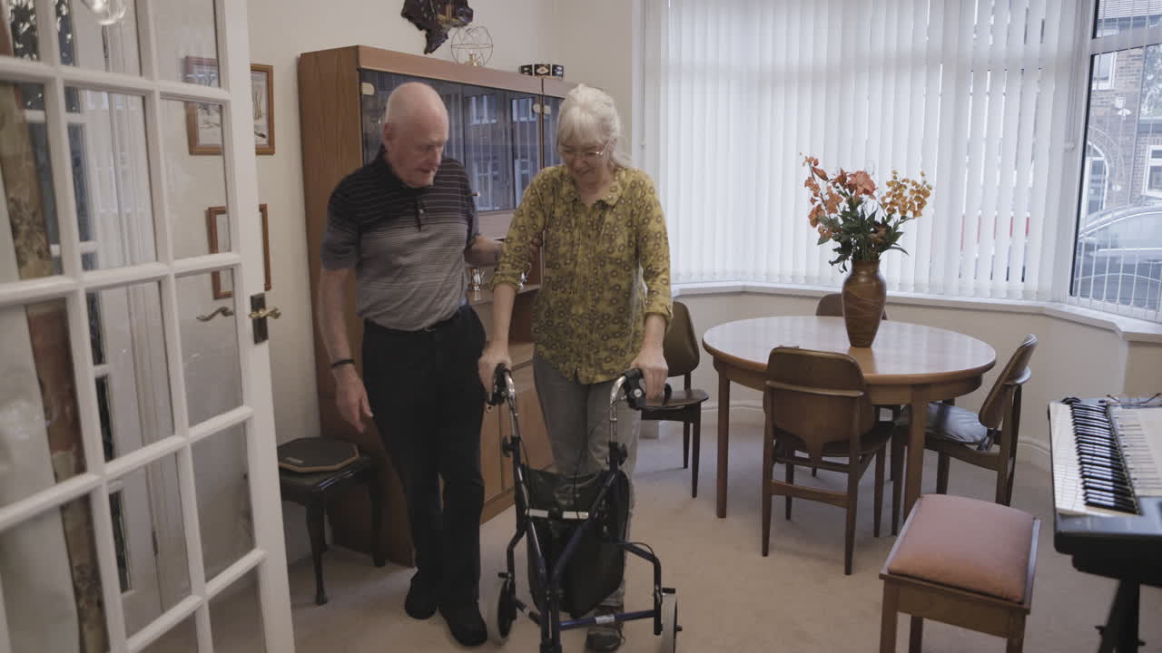 Elderly couple using a walker in their home
