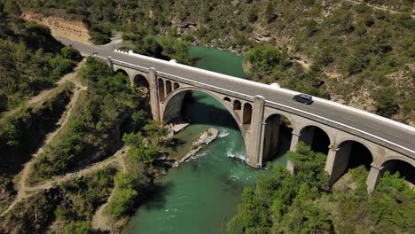 murillo de gallego bridge in huesca over turquoise river, surrounded by lush greenery, aerial view