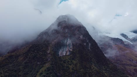 toma aérea circular de un pico de montaña con vegetación en un día de niebla en los andes