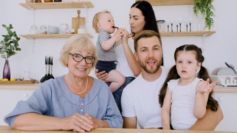 familia feliz mirando la cámara mientras hace una videollamada en la cocina 1