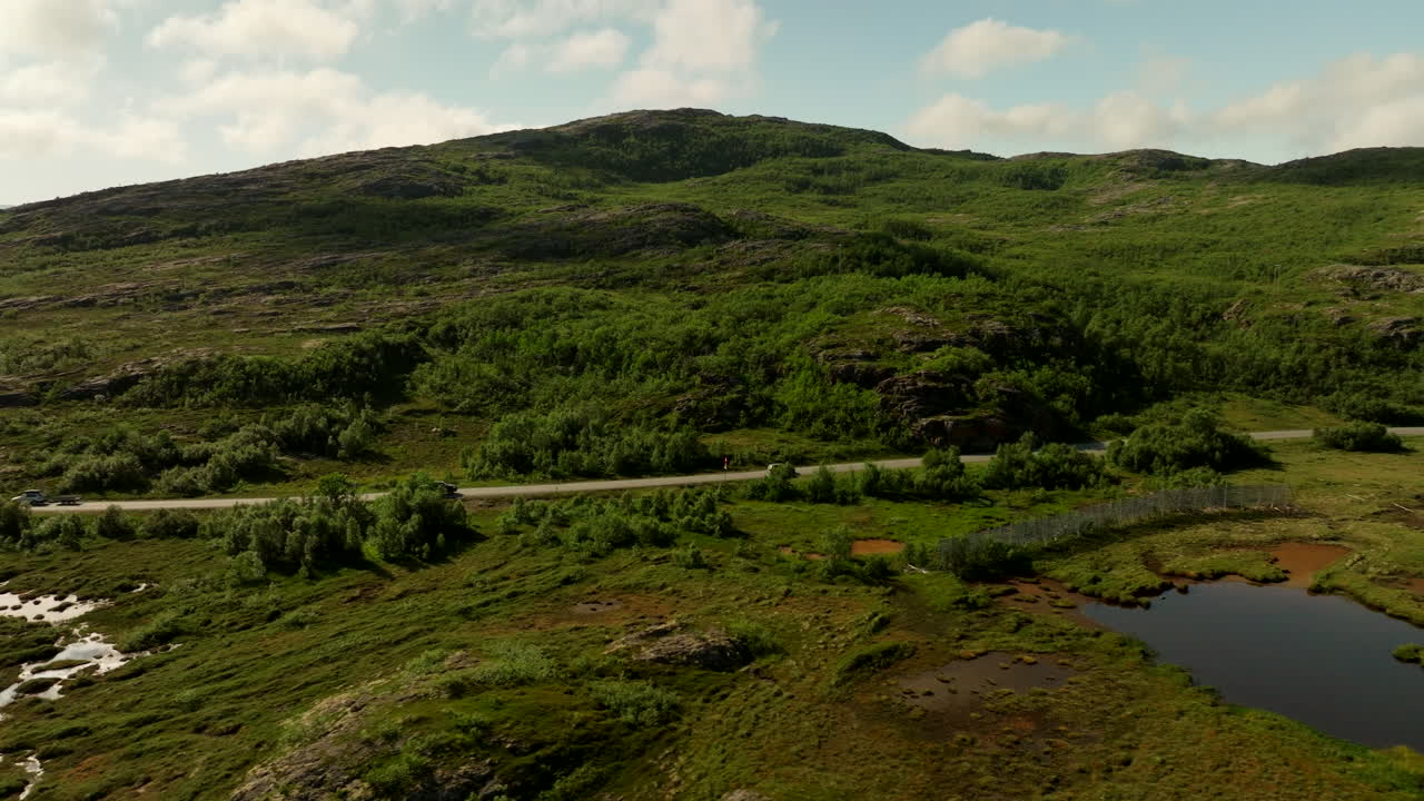 Vehicles drive through lush Kvaloya landscape in Northern Norway, aerial