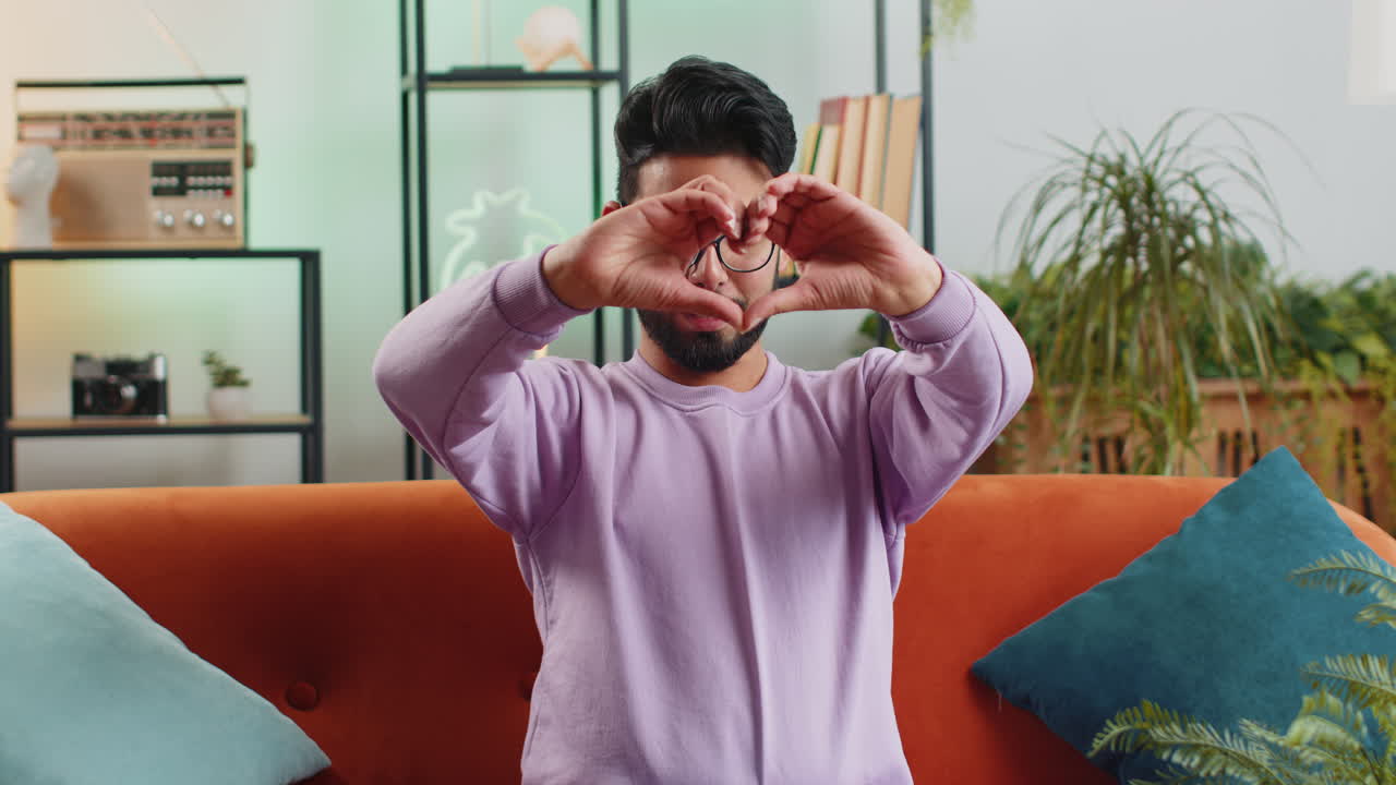 행복한 인디언 남자는 사랑의 상징을 만니다. 카메라에 심장 기호를 보여주고 로맨틱한 감정을 표현합니다.