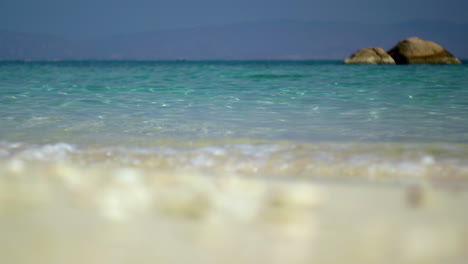 Nahaufnahme-Eines-Tropischen-Weißen-Sandstrandes-Mit-Muscheln-Und-Einer-Malerischen,-Verträumten-Paradiesischen-Meereslandschaft-In-Der-Ferne