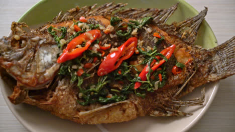 fried tilapia fish with basil chili garlic sauce on top - homemade food style