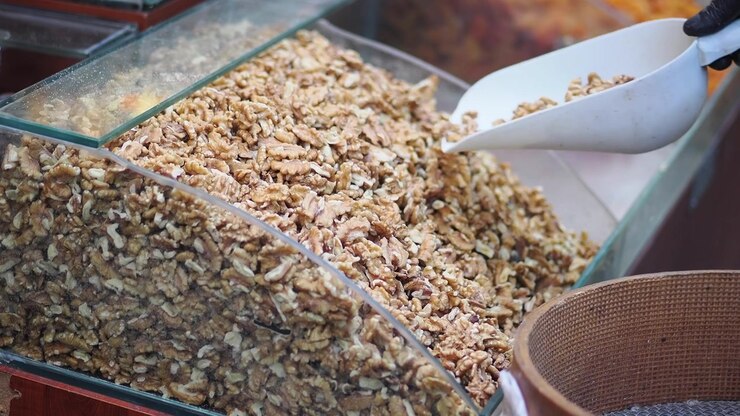 Vendor Scooping Walnuts from a Glass Display Case