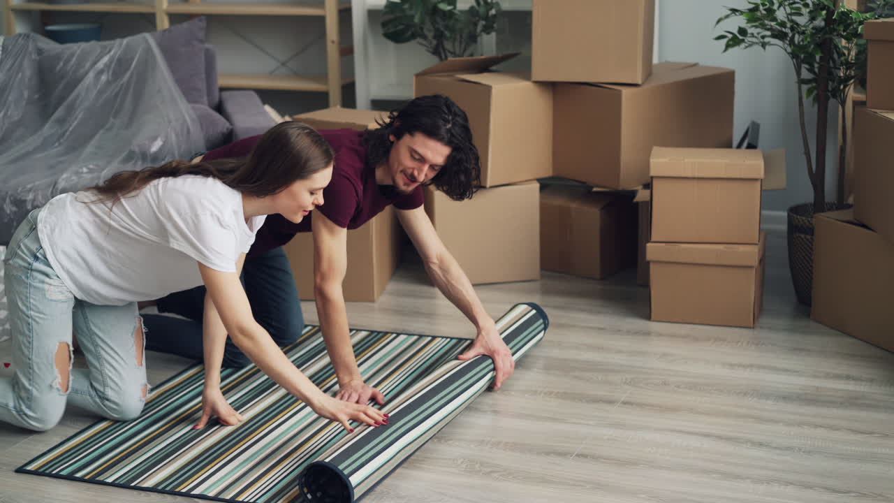 Couple Unpacking and Placing Carpet in Their New Home